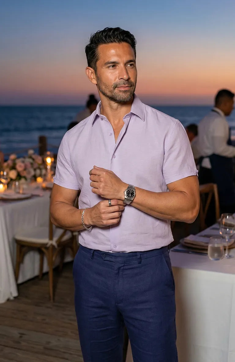 Man adjusting his Beckford Men’s Linen Shirt in Violet at an outdoor event with tables and people in the background
