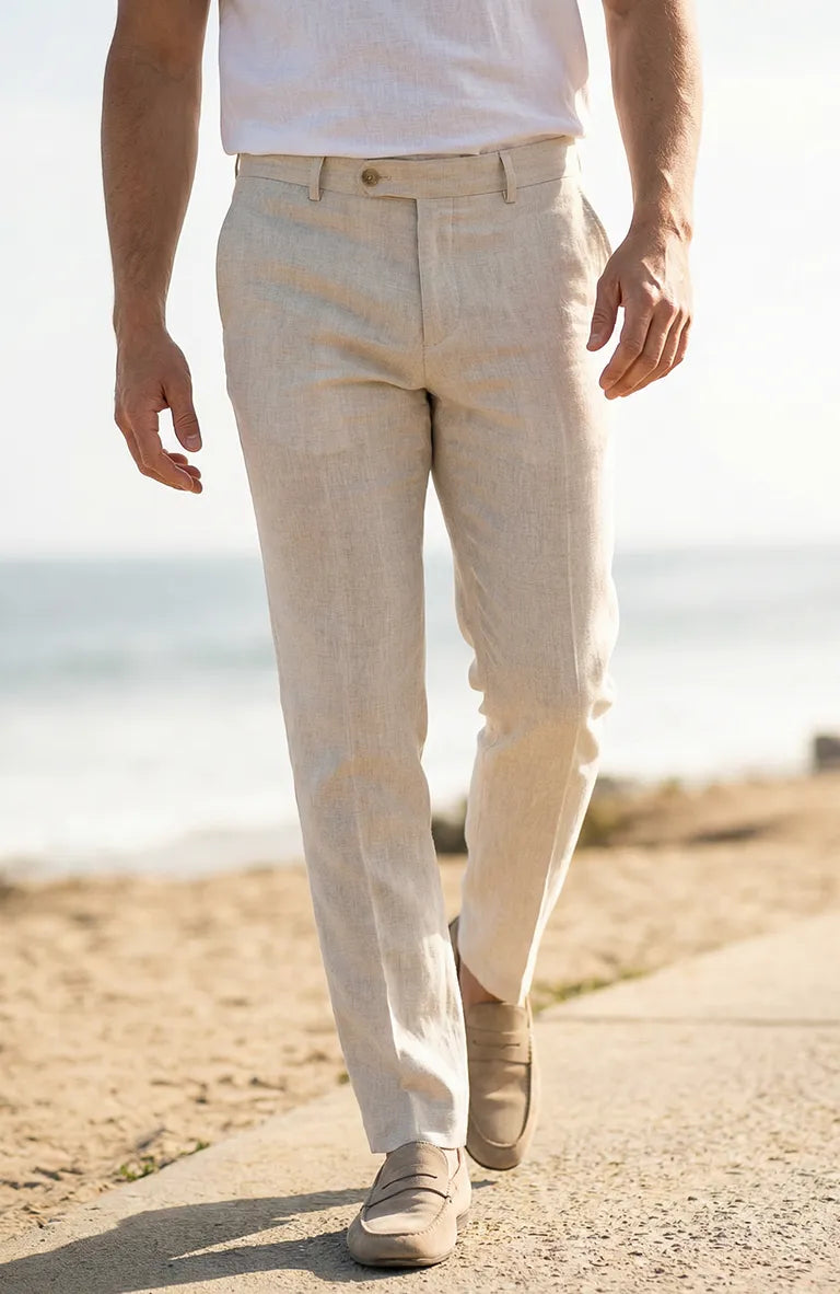Person wearing Men's Verona Linen Pants in Natural and a white shirt on a beach.